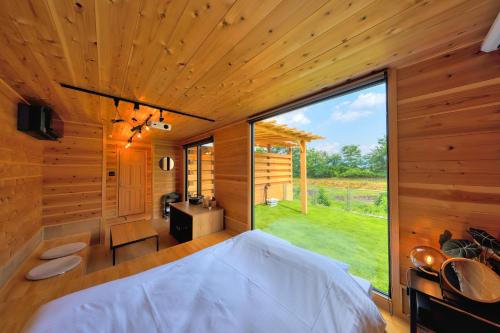 a bedroom with a bed and a large window at Almin Base 全室プライベートサウナ付きの宿 in Minami Alps
