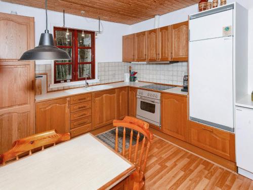 a kitchen with wooden cabinets and a white refrigerator at 4 person holiday home in Læsø in Læsø