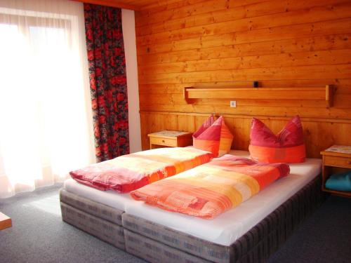 two beds in a bedroom with wooden walls at Haus Wendelin in Fulpmes