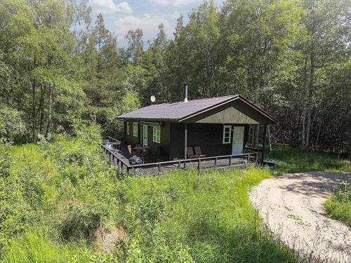 a small cabin in the woods next to a dirt road at 4 person holiday home in Læsø in Læsø