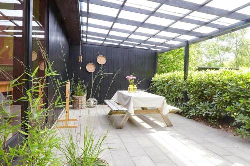 a patio with a table and a bench under a roof at 10000-1-Rorvig-Birkealle-2-A in Rørvig