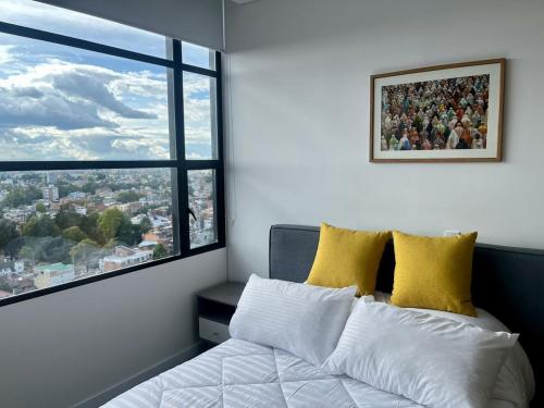 a bedroom with a bed with yellow pillows and a window at Tu espacio acogedor en el Centro Internacional in Bogotá