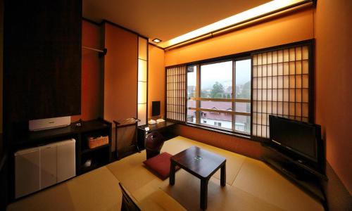 a living room with a table and a large window at Unzen Fukudaya in Unzen