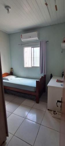 a small bedroom with a bed and a window at Casa Cop 30 em condomínio in Ananindeua