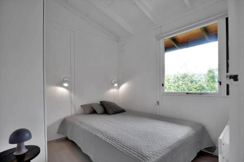 a white bedroom with a bed and a window at 12280-Sjaellands-Odde-Pumavej-8 in Tjørneholm