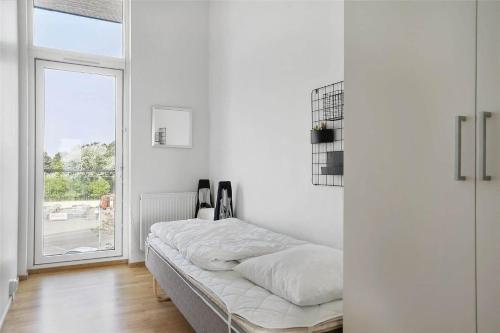Un dormitorio blanco con una cama y una ventana. en 0427-Romo-Nordre-Havnevej-58, en Havneby
