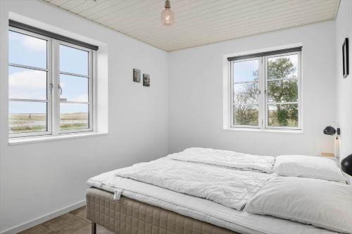 a bed in a white room with two windows at 0003-Romo-Vestervej-39 in Toftum
