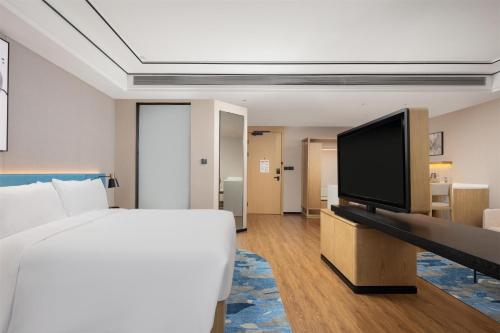 a bedroom with a bed and a flat screen tv at Hilton Garden Inn Zhuji East in Shaoxing
