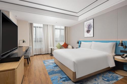 a hotel room with a large bed and a flat screen tv at Hilton Garden Inn Zhuji East in Shaoxing