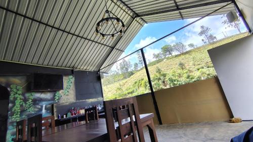 a room with a table and chairs and a large window at Grounder's River Cabin in Nuwara Eliya