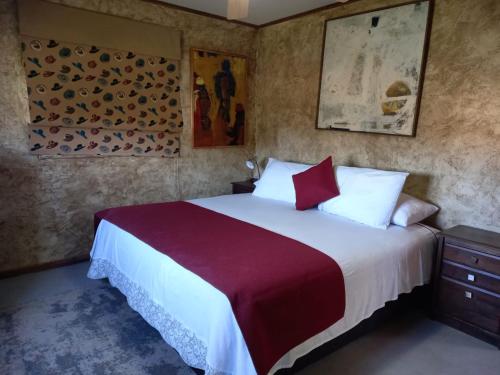 a bedroom with a large bed with red and white sheets at Texas Limache in Limache