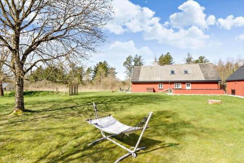 a chair sitting in a field in front of a red barn at BL1454-Pandrup-Rodhusvej-215 in Pandrup