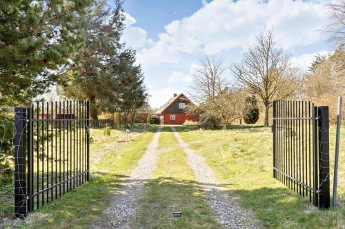 an open gate in a field with a red barn at BL1454-Pandrup-Rodhusvej-215 in Pandrup