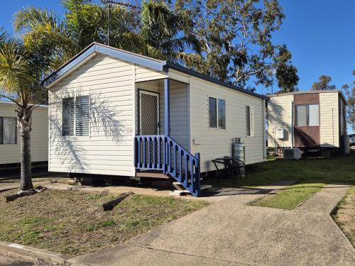 a small white house with a porch and a tree at Tamworth Holiday Park in Tamworth