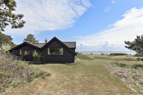 a black house sitting on top of a field at 12274-Sjaellands-Odde-Lyngvang-13 in Tjørneholm