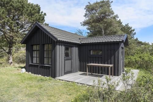 a black shed with a bench in a field at 12274-Sjaellands-Odde-Lyngvang-13 in Tjørneholm
