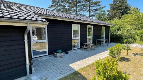a black house with a patio and a table at 11185-Nykobing-Sj-Lynghaekken-8 in Nykøbing Sjælland