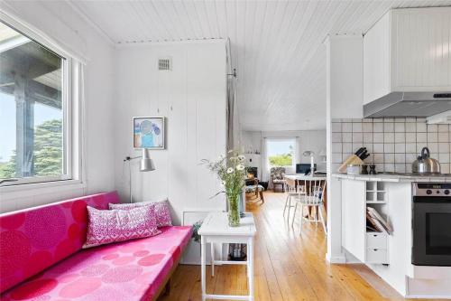 a living room with a pink couch and a kitchen at 16615-Farevejle-Alfestien-10 in Fårevejle