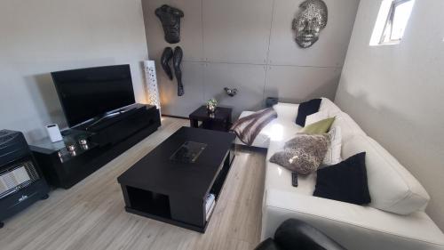 a living room with a white couch and a tv at 391 at SoHo in Sandton