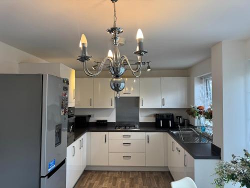 una cocina con armarios blancos y una lámpara de araña en Alvea Living, en Bushbury