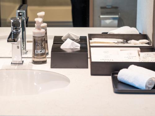 a bathroom counter with a sink and hygiene products on it at Hotel Crown Palais Kobe in Kobe