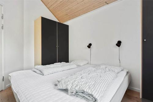 a bedroom with a white bed with a black cabinet at 16610-Farevejle-Mejsevaenget-26 in Fårevejle