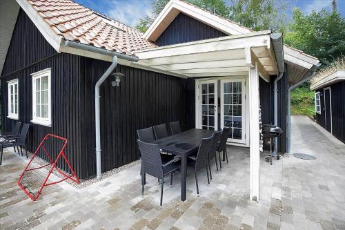a black house with a table and chairs on a patio at 16610-Farevejle-Mejsevaenget-26 in Fårevejle