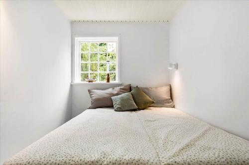 a bed in a white room with a window at 10040-Rorvig-Lyngvaenget-10 in Rørvig