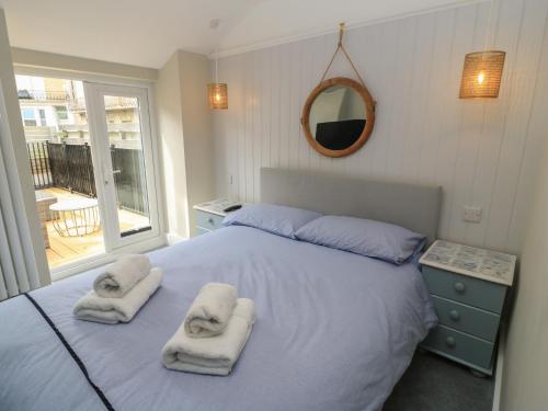 a bedroom with towels on a bed with a mirror at Still Waters in Swanage