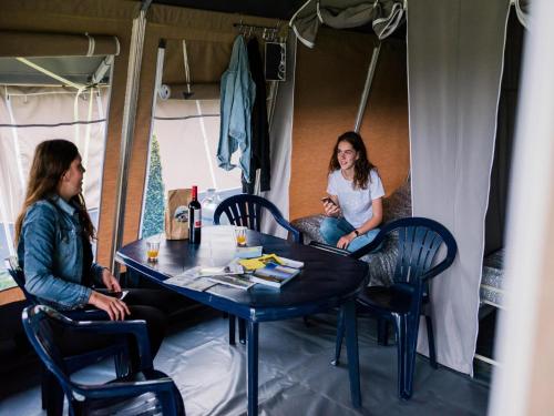 two women sitting at a table in a trailer at Tent Lodge near Echternach Nature Park in Echternacherbrück