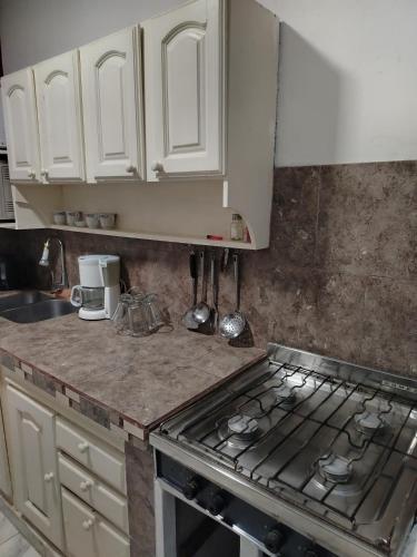 a kitchen with white cabinets and a stove top oven at LA Helena in Ezeiza