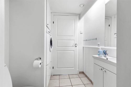 a white bathroom with a door and a sink at 11207-Nykobing-Sj-Havnevej-65-1-th in Nykøbing Sjælland