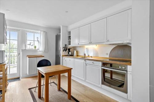 a kitchen with white cabinets and a wooden table at 11202-Nykobing-Sj-Havnevej-91-1-th in Nykøbing Sjælland