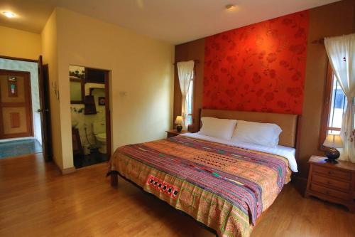 a bedroom with a bed with a red wall at Plumeriahome near Chiangmai Airport in Chiang Mai