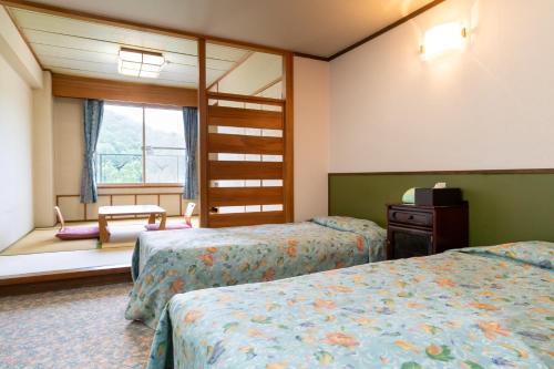 a hotel room with two beds and a window at Diamond Shiga in Yamanouchi