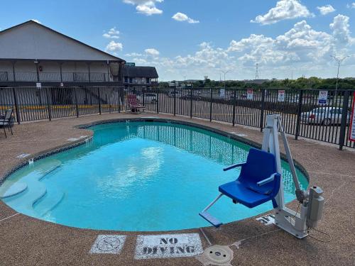 a blue chair sitting next to a swimming pool at Studio 6 Suites Mesquite, TX – Gross Rd. in Mesquite
