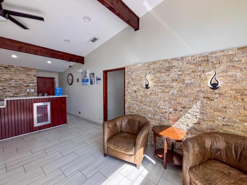 a lobby with two chairs and a table and a brick wall at Studio 6 Suites Mesquite, TX – Gross Rd. in Mesquite