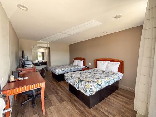 a hotel room with two beds and a desk at Studio 6 Suites Mesquite, TX – Gross Rd. in Mesquite