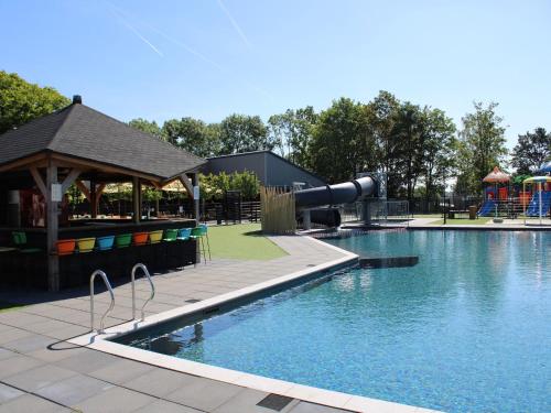a swimming pool with a slide and a playground at Holiday home on the recreational lake in Lathum