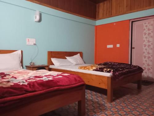 two beds in a room with red and blue walls at EHI Homestay Kurseong in Kurseong