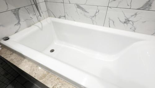 a white bath tub in a bathroom with marble walls at 알마비즈니스호텔 in Jincheon