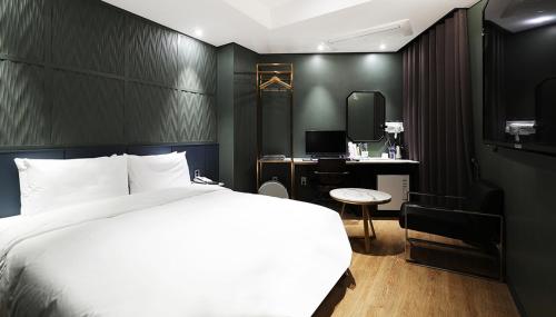 a bedroom with a white bed and a desk at 알마비즈니스호텔 in Jincheon