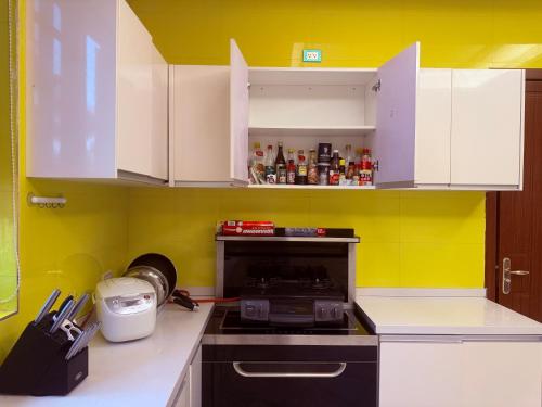 a kitchen with white cabinets and a yellow wall at Hanamitsu Hotel & Spa in Garapan