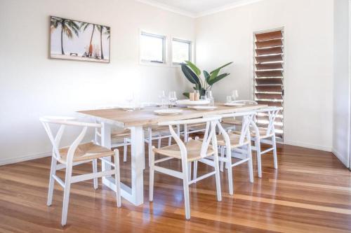a white dining room with a white table and chairs at Beachside House in Sebel Resort in Twin Waters
