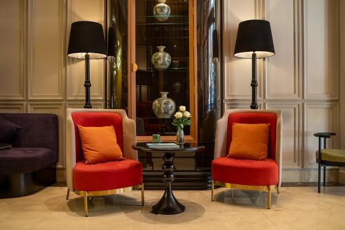 two chairs with orange pillows and a table in a room at Le Premier Hotel & Rooftop Bar in Hanoi