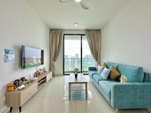a living room with a blue couch and a tv at Macrolink Medini Legoland by Stayrene in Kangkar Pendas