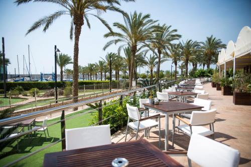 a row of tables and chairs at a restaurant with palm trees at Senator Águilas in Águilas