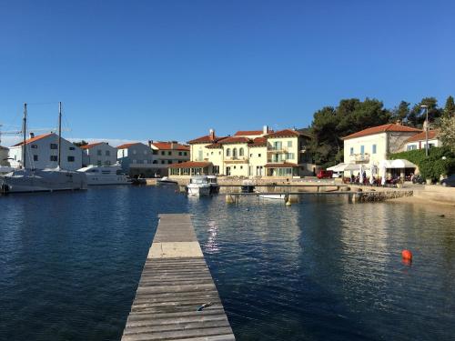 a dock in a body of water with houses at Hotel Televrin in Nerezine