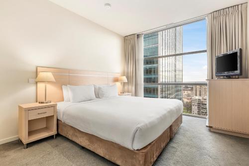 a bedroom with a large bed and a large window at Nolo Apartments Lonsdale St in Melbourne