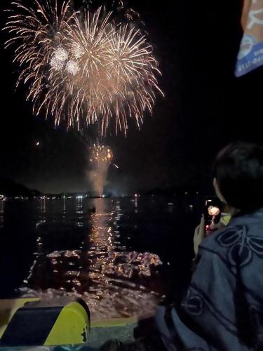 a person taking a picture of fireworks in the water at TAKUMI-AN Private Ancient House and Garden in Numazu